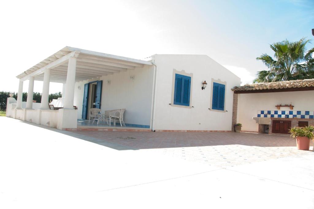 a white house with blue windows and a patio at Villa Ilaria in Marzamemi