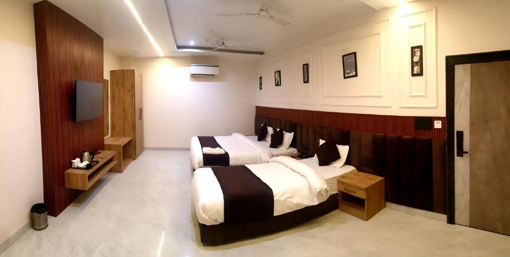 a hotel room with two beds and a tv at Hotel The Coal in Alīgarh