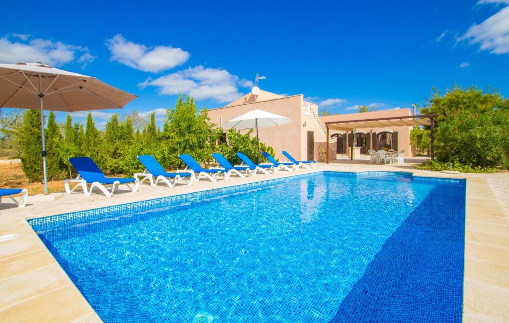 a pool with chairs and umbrellas next to a house at Ses Comunes in Campos