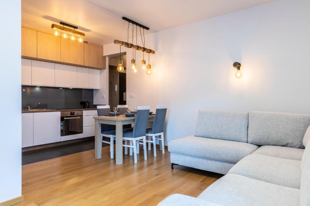 a living room with a couch and a table with chairs at Tatry Top Apartamenty Granitica centrum in Zakopane