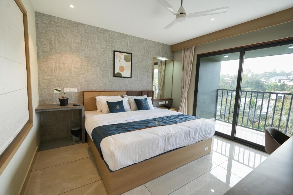 a bedroom with a large bed and a balcony at Rasha Suites in Kalpetta