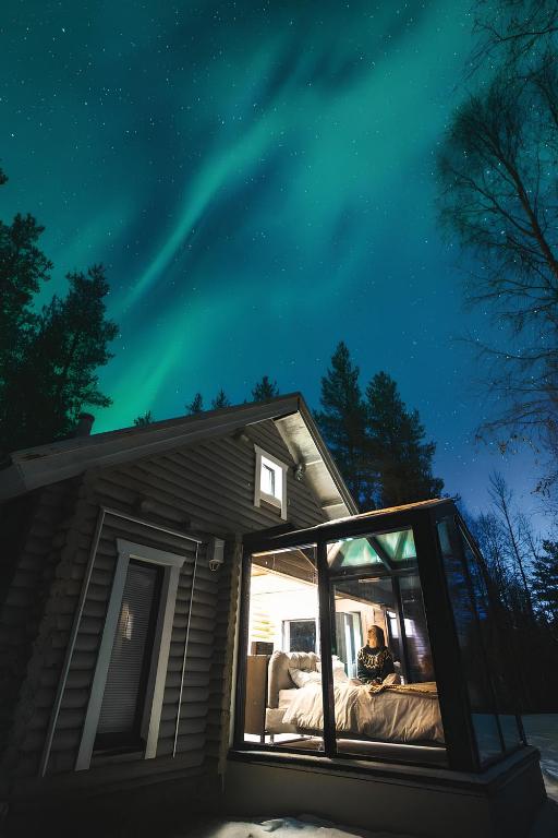 a person is sitting in a window of a house at Sky Lodging - sleeping under the stars - private cottage in Rovaniemi