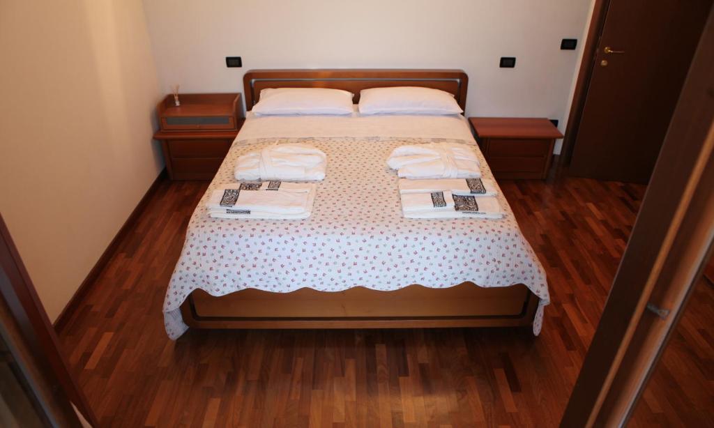 a bedroom with a bed with white sheets and wooden floors at Recanati Family in Recanati