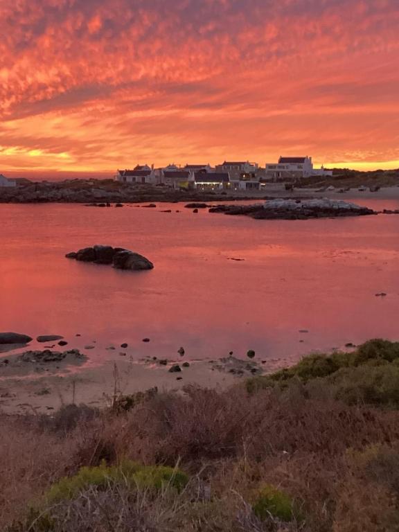 a sunset over a body of water with buildings at Verdoesie Jacobsbaai in Jacobs Bay