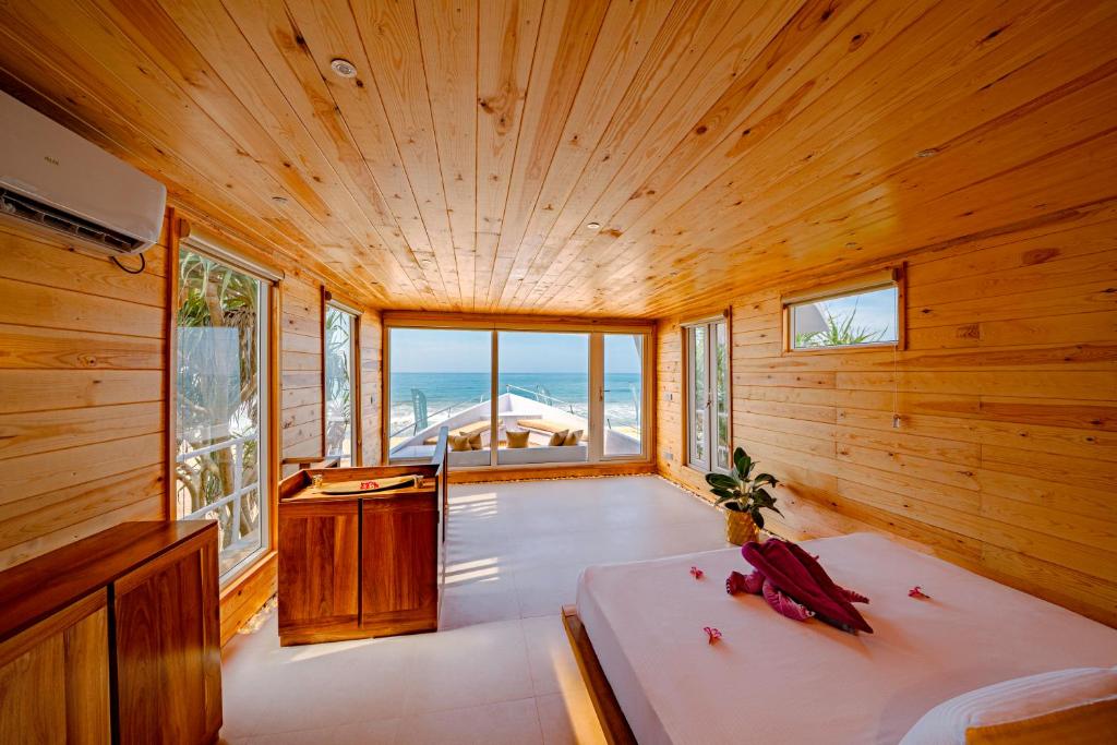 a wooden room with a bed and a view of the ocean at Jungle Beach Ahungalla in Ahungalla