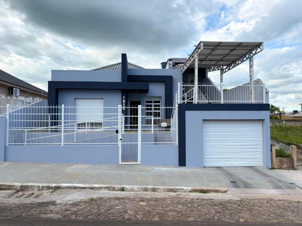 a blue house with two garage doors and a fence at Suite Privativa in Dom Pedrito