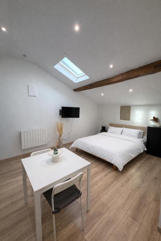 a bedroom with a white bed and a table at Le cocon - STUDIO- MACON in Saint-Laurent-sur-Saône