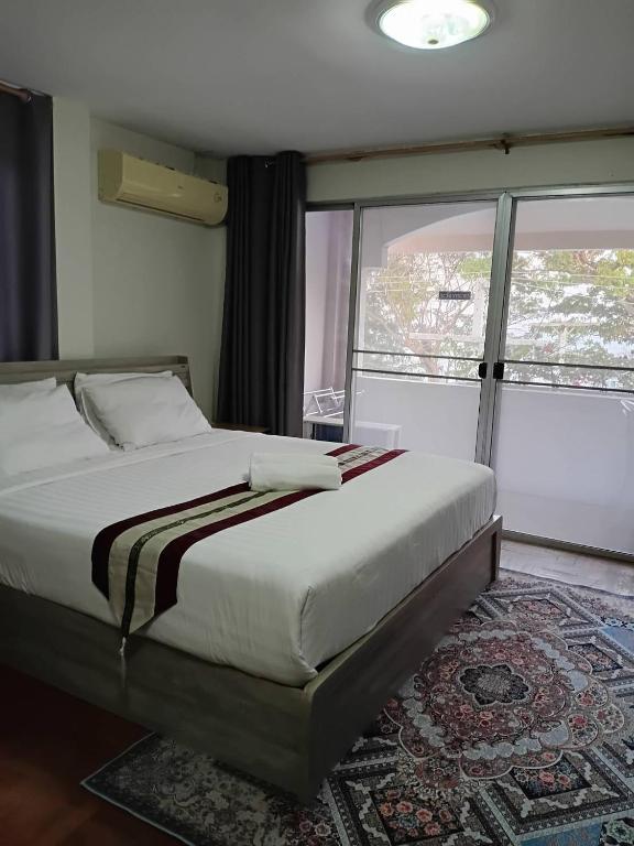 a bedroom with a bed and a large window at Beachfront Hotel Cha Am in Cha Am