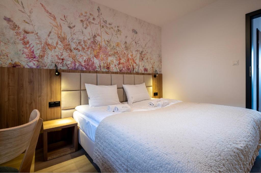 a bedroom with a large white bed and a wall at Apartamenty Beski in Szczyrk
