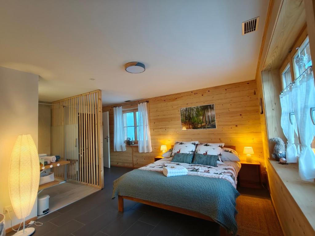 a bedroom with a bed and a wooden wall at B&B Le Chalet in Les Sciernes d'Albeuve