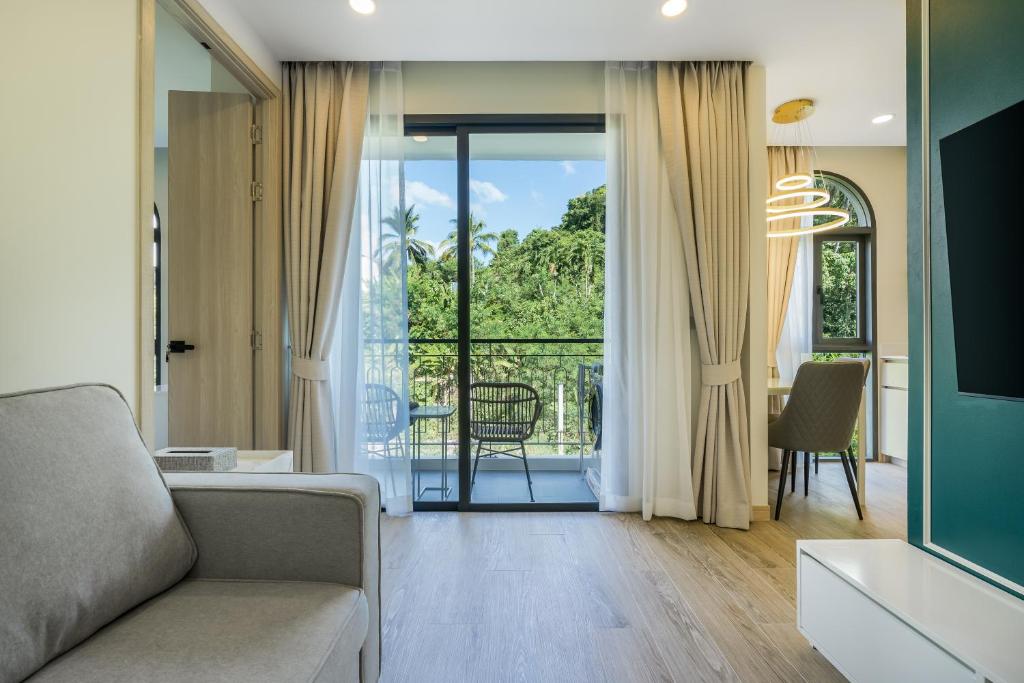 a living room with a couch and a balcony at Palmetto Park Residence in Karon Beach