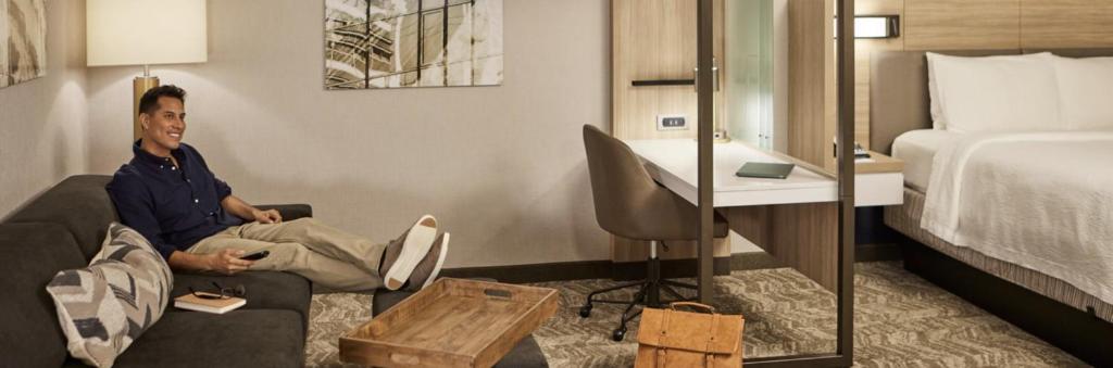 a man sitting on a couch in a hotel room at SpringHill Suites by Marriott Surprise in Surprise