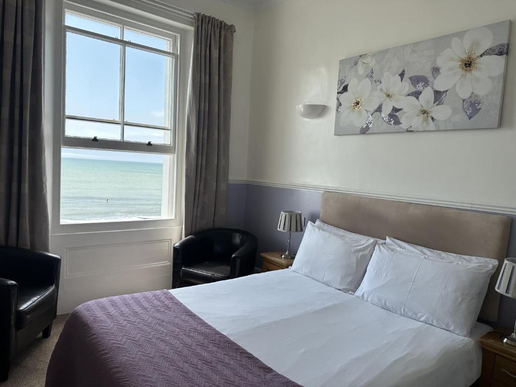 a bedroom with a bed and a window with the ocean at The Lindum in Hastings