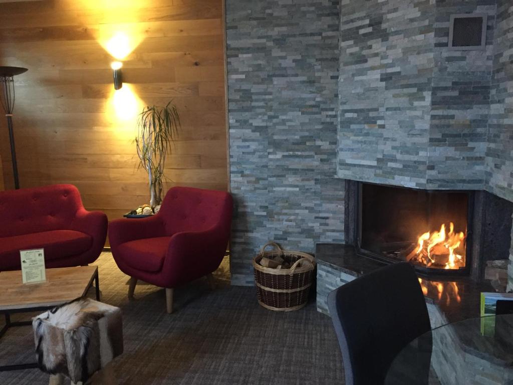 a living room with a fireplace and two red chairs at Hôtel Panorama in Munster