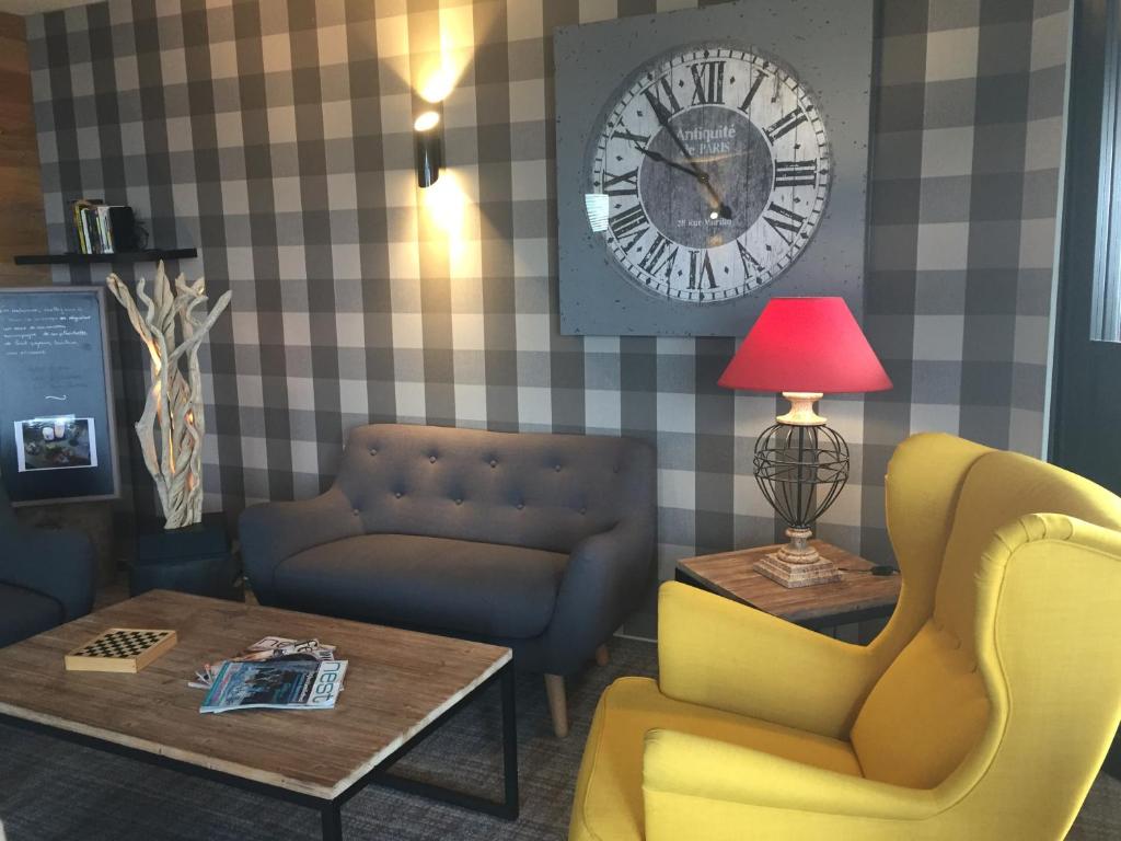 a living room with a clock and a table and chairs at Hôtel Panorama in Munster