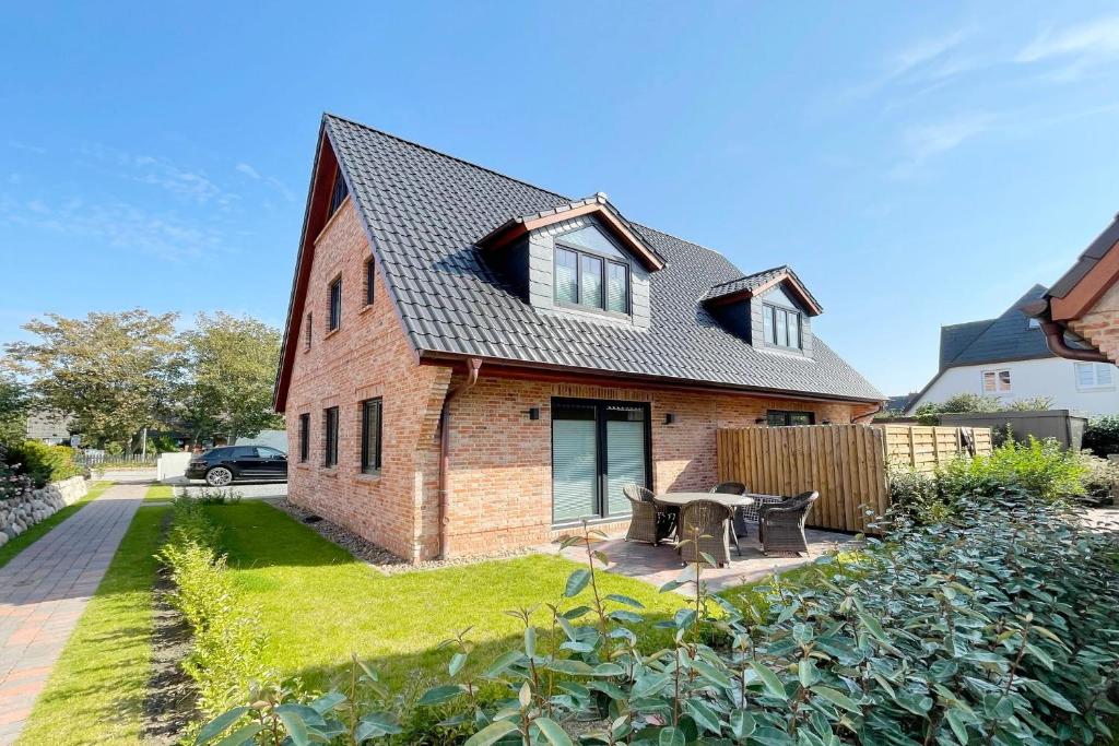 a brick house with a patio in the yard at Engels Hüs in Tinnum