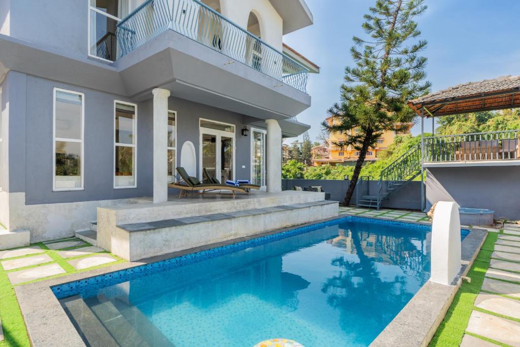 a home with a swimming pool and a house at Casa Mandala by ELIVAAS in Candolim