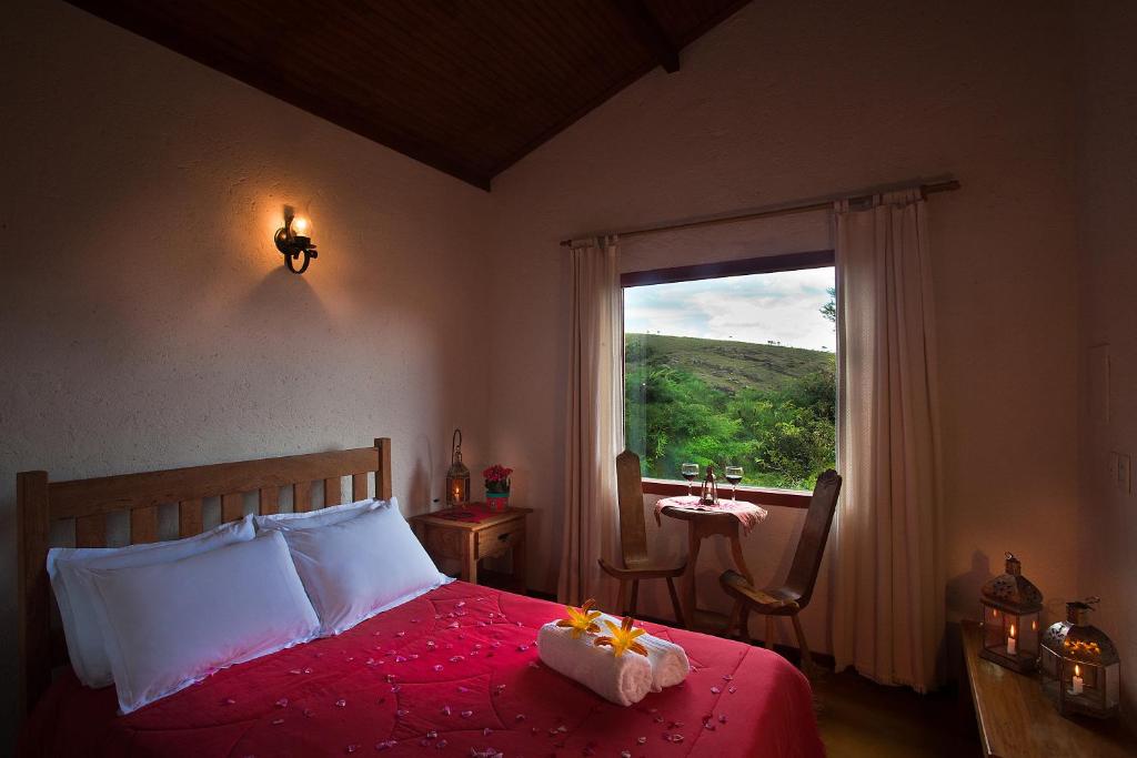 a bedroom with a bed and a window with a table at Vila das Artes Chales in Lavras Novas