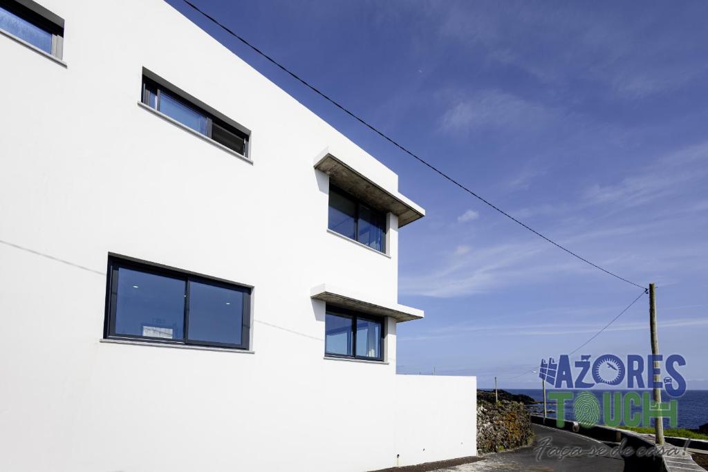 a white building with the ocean in the background at Casa Menino do Mar in Porto Judeu