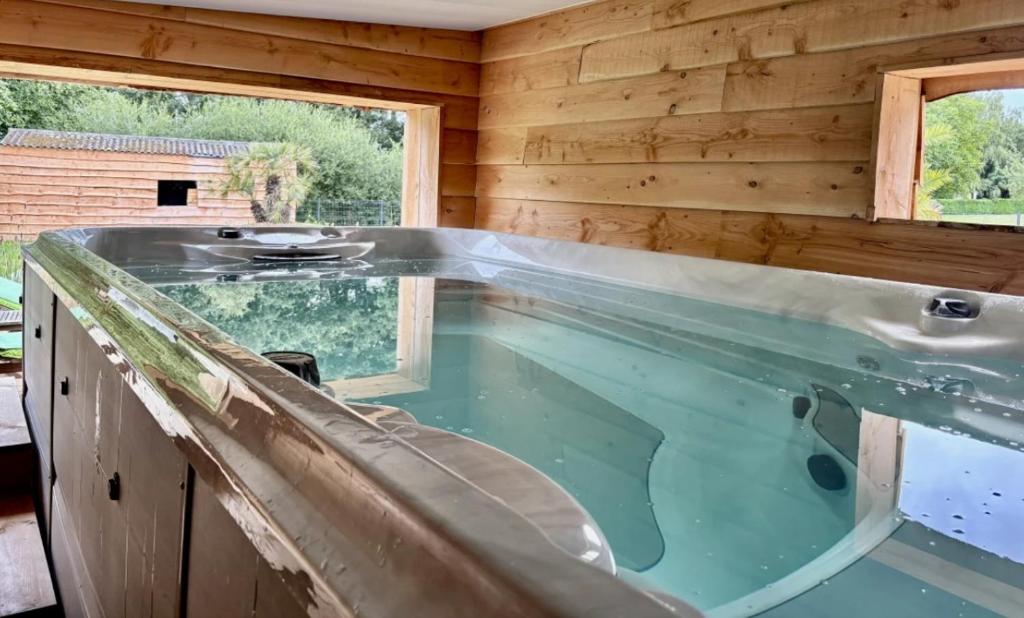 a swimming pool in a wooden house with a tub at Natur eau Bulle in Ploufragan