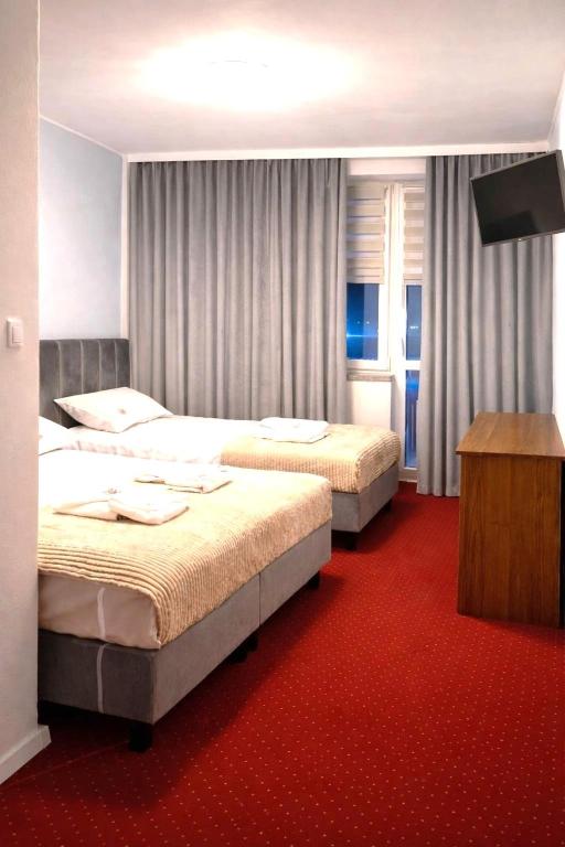 two beds in a hotel room with a red carpet at Motel Jaśminowy Dworek Człekówka 67 B in Człekowka