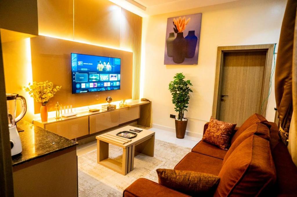 a living room with a couch and a flat screen tv at EXQUISITE Home 2 Abuja in Abuja