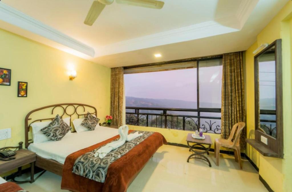 a bedroom with a bed and a balcony at Hotel Indira Nature Valley Mahabaleshwar in Mahabaleshwar