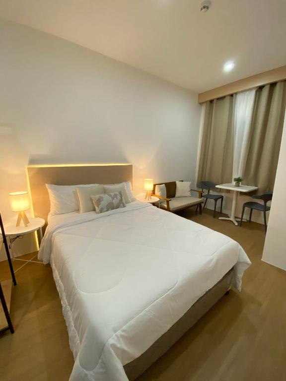 a large white bed in a room with tables and chairs at The Studio Suites in Maribago