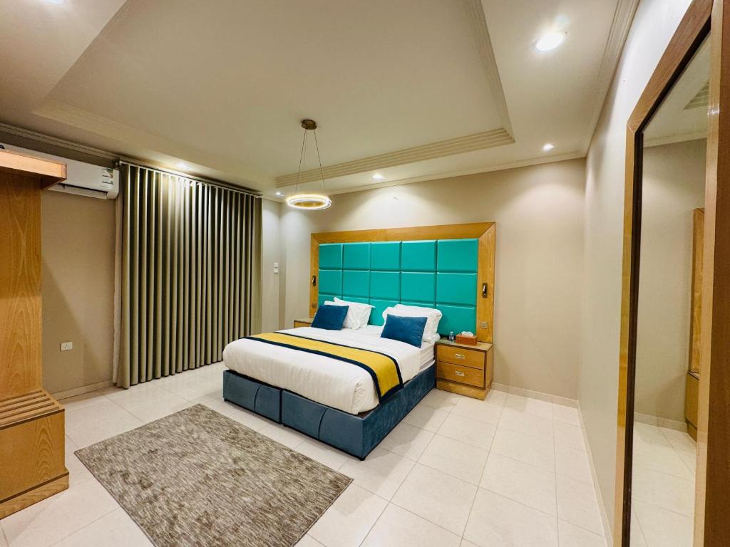 a bedroom with a bed with a blue headboard at Rove Appartments in Taif