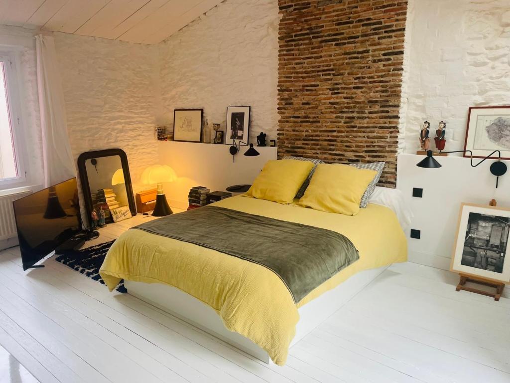a bedroom with a bed and a brick wall at Maison Solar Trentemoult in Rezé