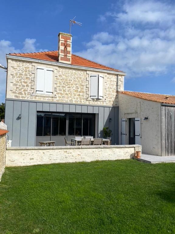 a house with a patio and a grass yard at L'Olivier in Charron