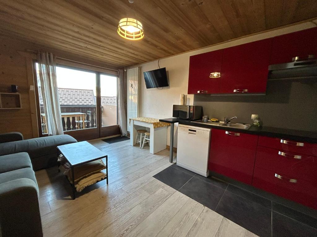 une cuisine avec des armoires rouges et un salon dans l'établissement Studio équipé / centre station, aux Carroz d'Arâches