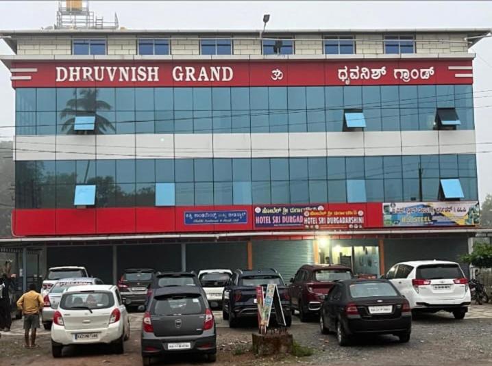 a parking lot with cars parked in front of a car dealership at Dhruvanish Grand in Sringeri