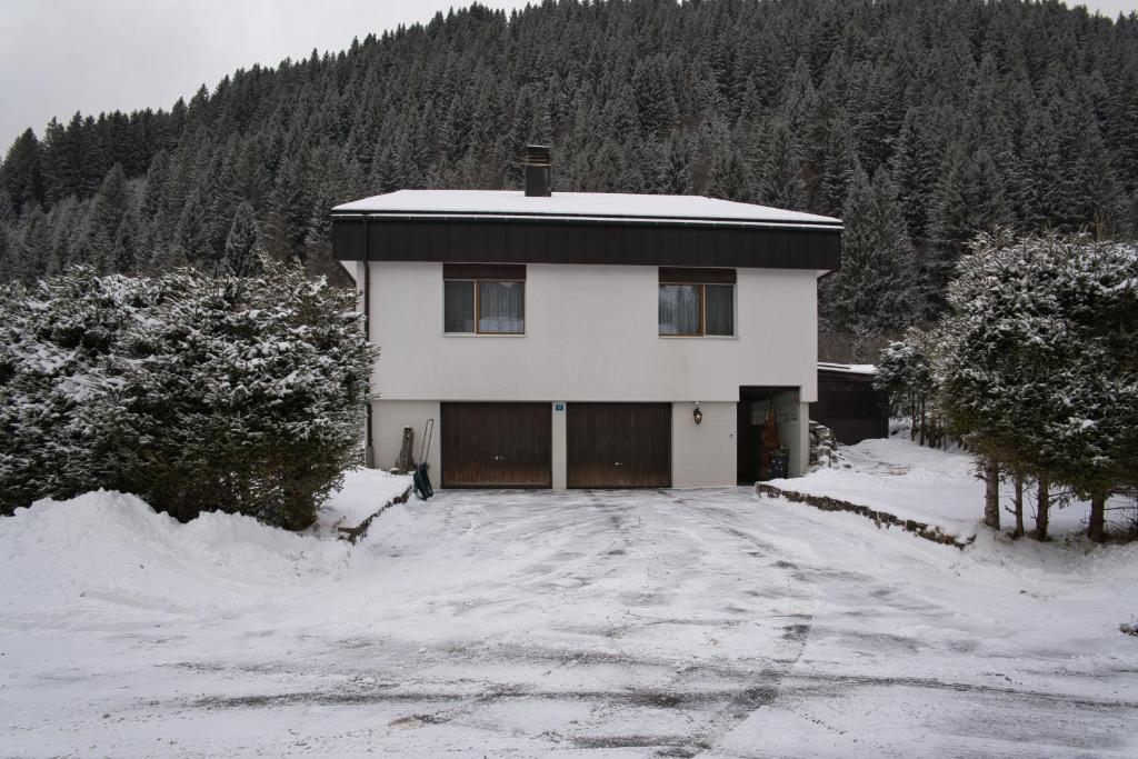 a white house with a garage in the snow at Haus Panorama in Schwarzsee