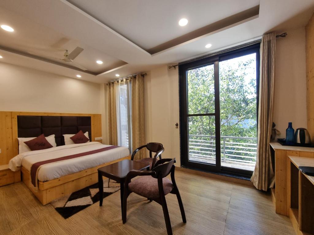 a bedroom with a bed and a desk and a window at Nomad Uber Hotel - Near Mall Road Dalhousie in Dalhousie