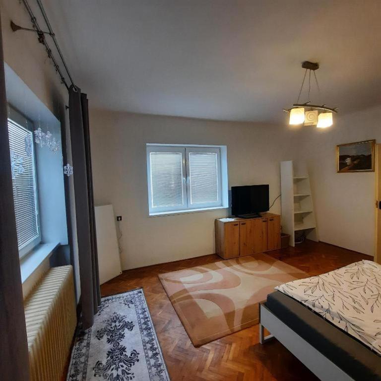 a bedroom with a bed and a tv and two windows at Pension Paradise Slowakia in Pastovce