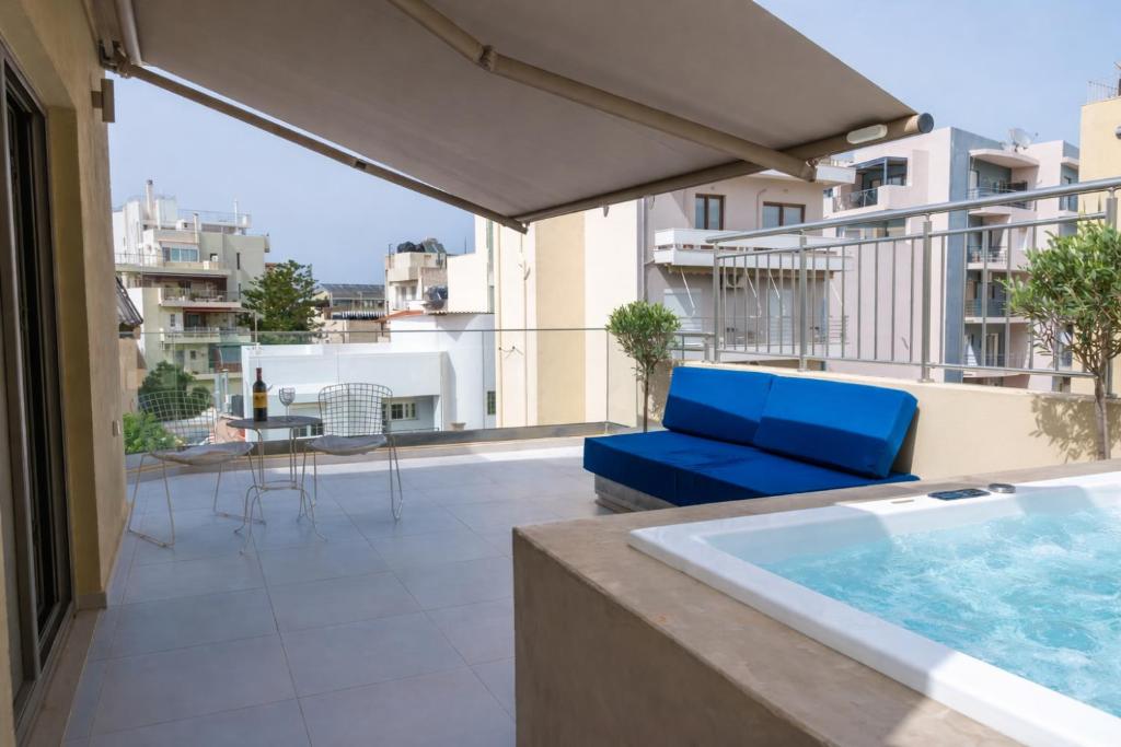 a balcony with a blue couch and a hot tub at Notos Boutique Apartments 3 with Private Jacuzzi in Heraklio