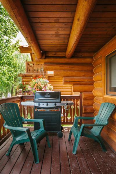 two chairs and a grill on a porch of a cabin at Great Northern Resort in West Glacier