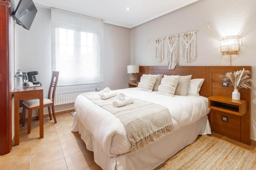 a bedroom with a large white bed and a desk at Habitaciones Guriezo in El Puente