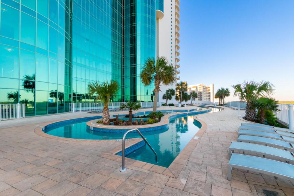 a pool in the middle of a building with palm trees at Turquoise Place Beachside Retreat in Orange Beach