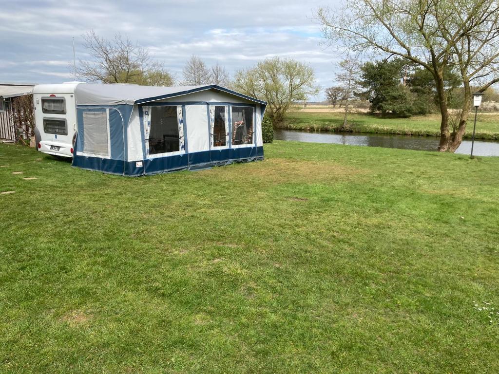 a rv parked in a field next to a river at Mietwohnwagen S1 am Flussufer in Wienhausen