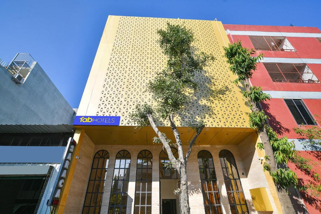 a yellow building with a tree in front of it at FabHotel Saraca Inn in Indore