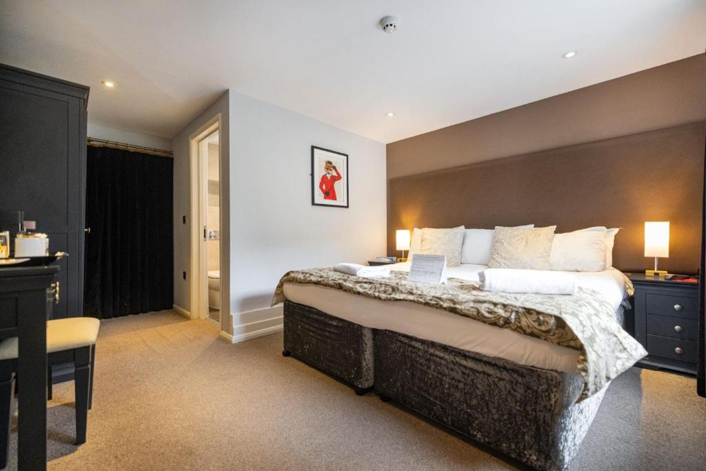 a bedroom with a large bed with a laptop on it at The Redesdale in Moreton in Marsh