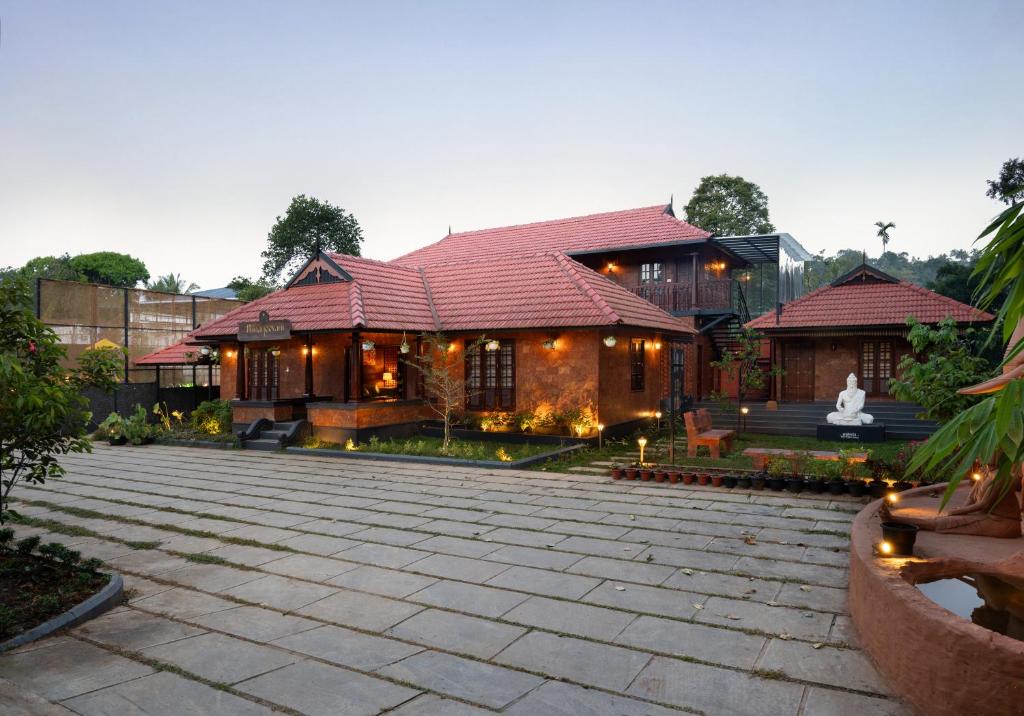 a house with a courtyard in front of it at Punarjeevani Ayurvedic Heritage in Vythiri