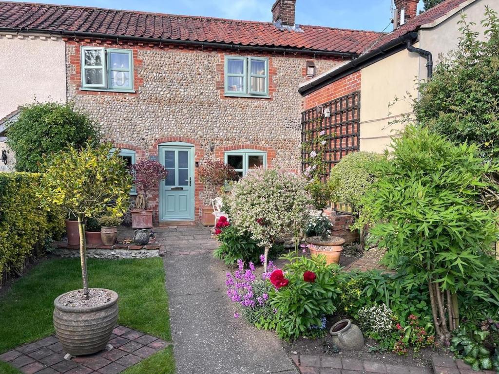 a brick house with a garden with flowers and plants at Pet Friendly, Border Cottage, Norfolk in Briston