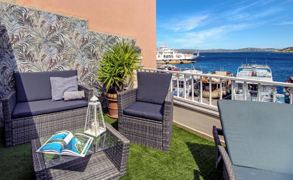 a balcony with two chairs and a table and a boat at Aquaemaris Apartment in La Maddalena
