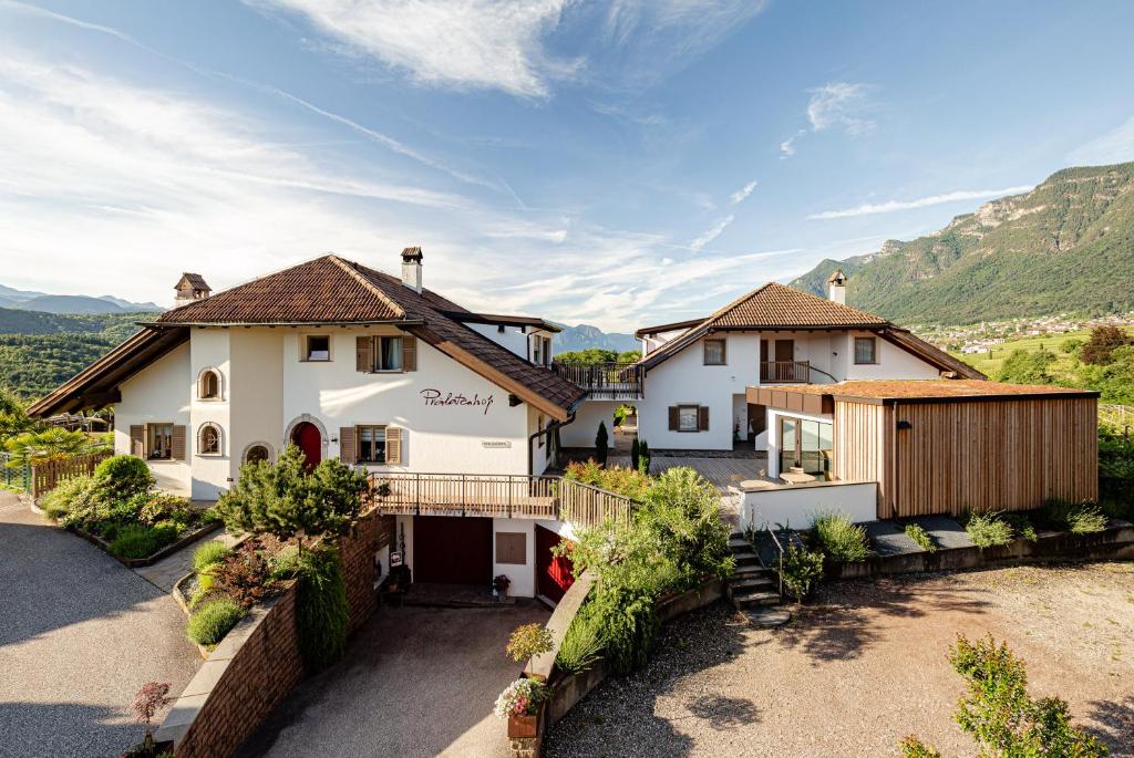 an aerial view of a house with mountains in the background at Prälatenhof Wine & Apartments in Caldaro