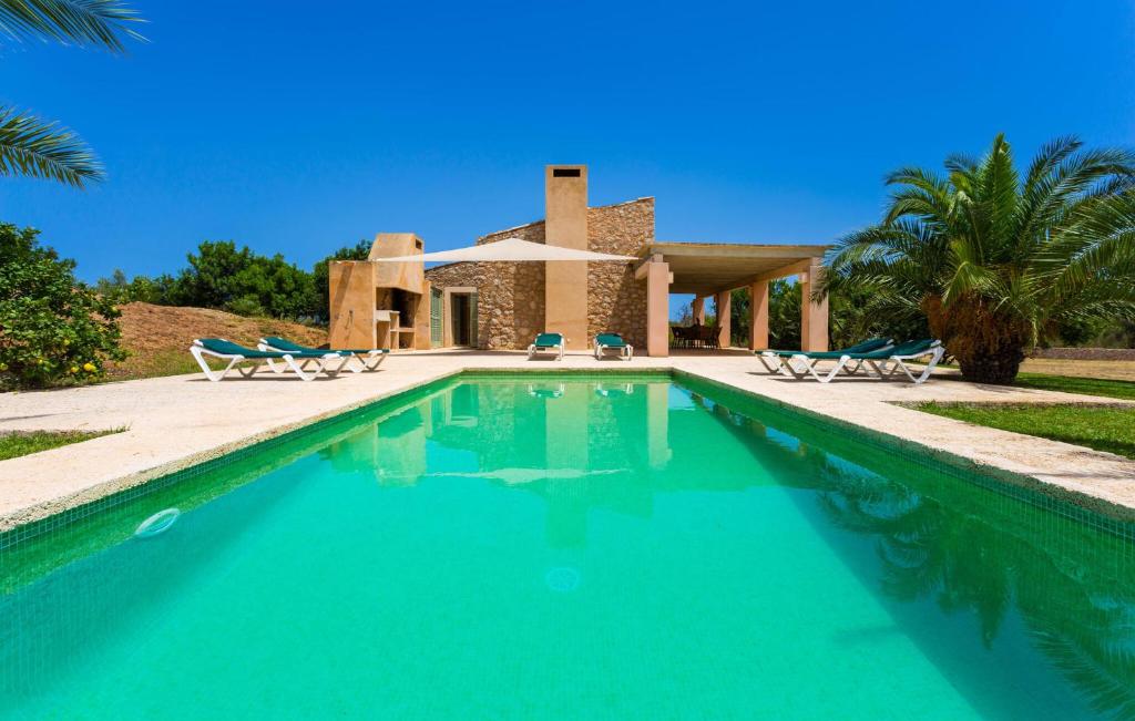 a swimming pool with chairs and a house at Clovetes in Son Servera
