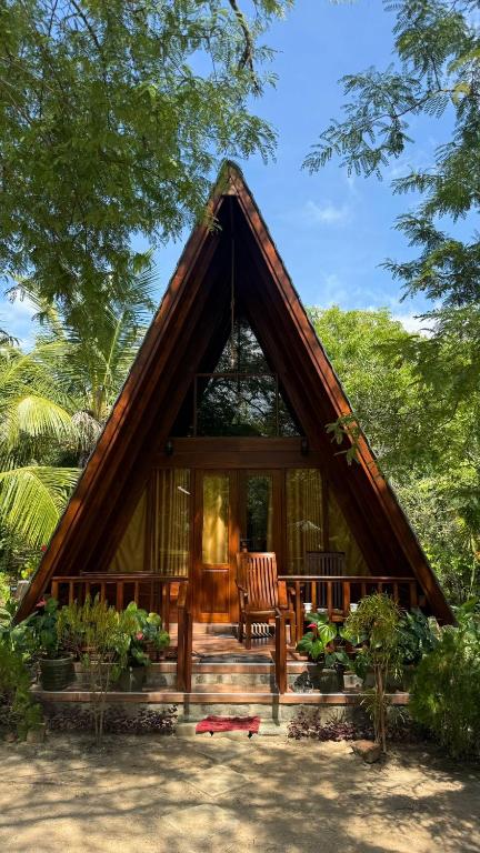 a small house with a thatched roof and a porch at Rock Pool Residence in Tangalle