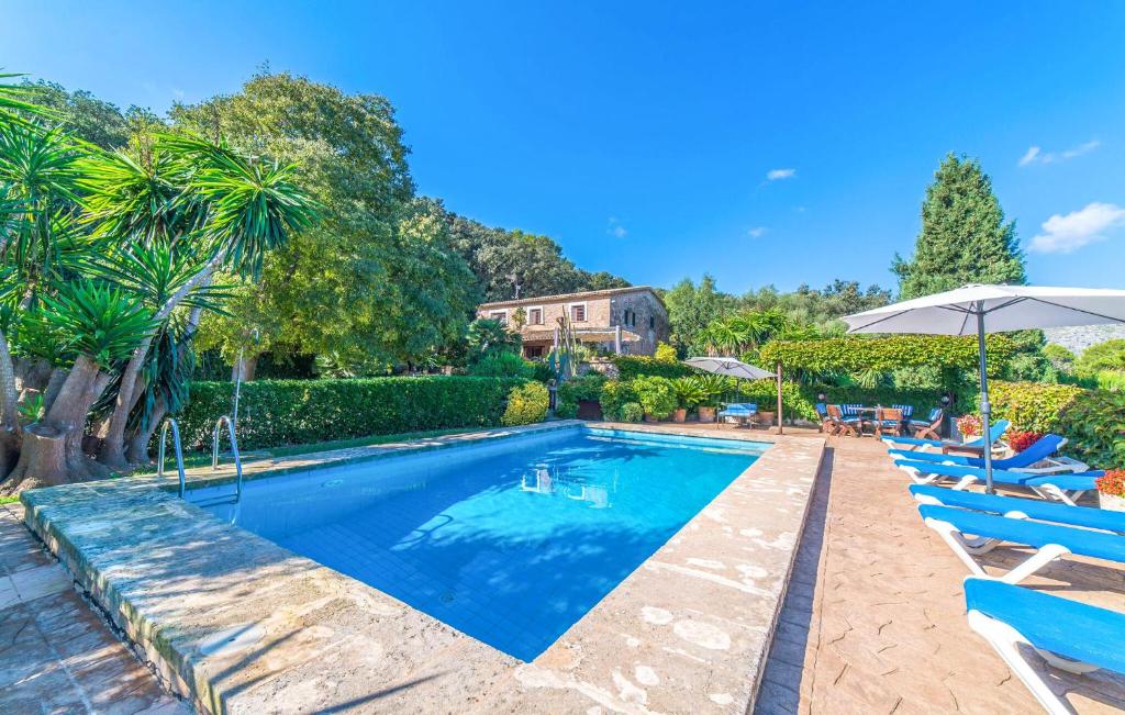 a swimming pool with blue chairs and an umbrella at Ca Les Estamenyes in Pollença